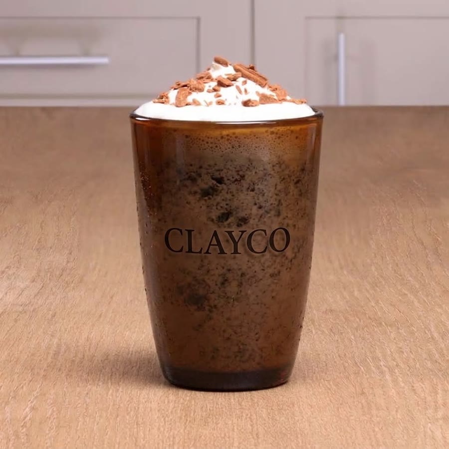 A CLAYCO frappé in a tall amber glass under whipped cream and chocolate